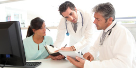 Doctors and a healthcare professional discussing patient care in a outpatient imaging center office.